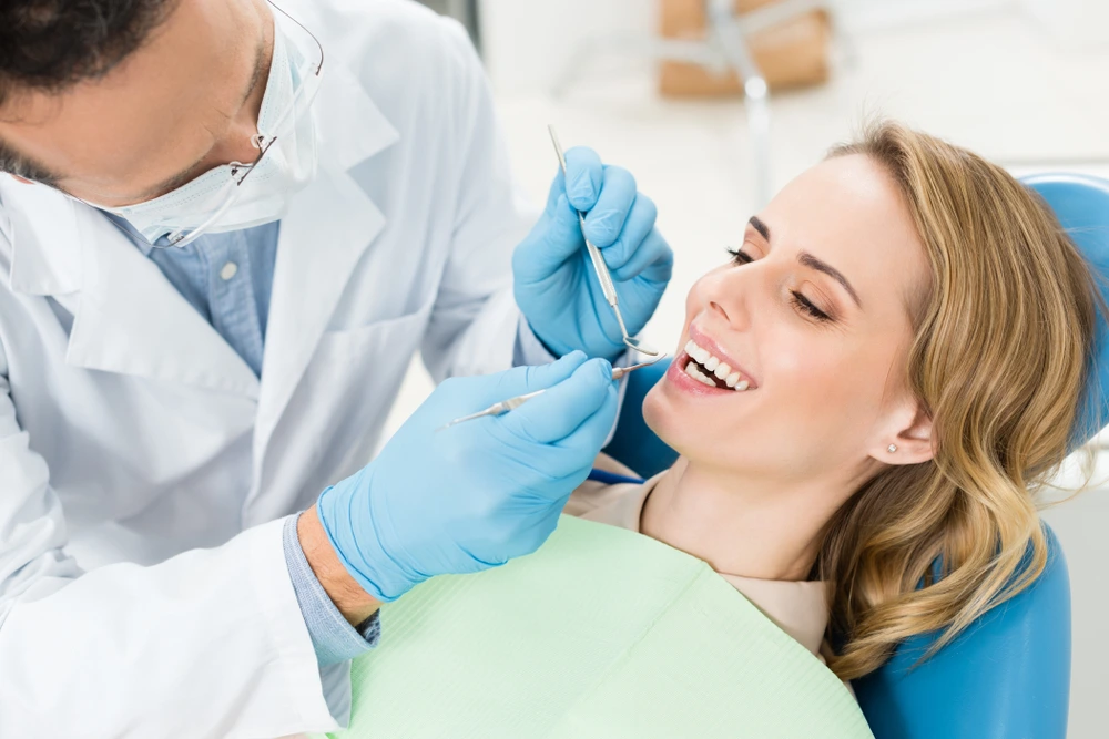 A female patient of City Family Dental Care is smiling while her dentist is checking her teeth